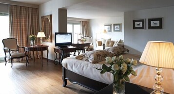 Una habitación de hotel con una cama, un escritorio, un televisor, una silla y una lámpara.