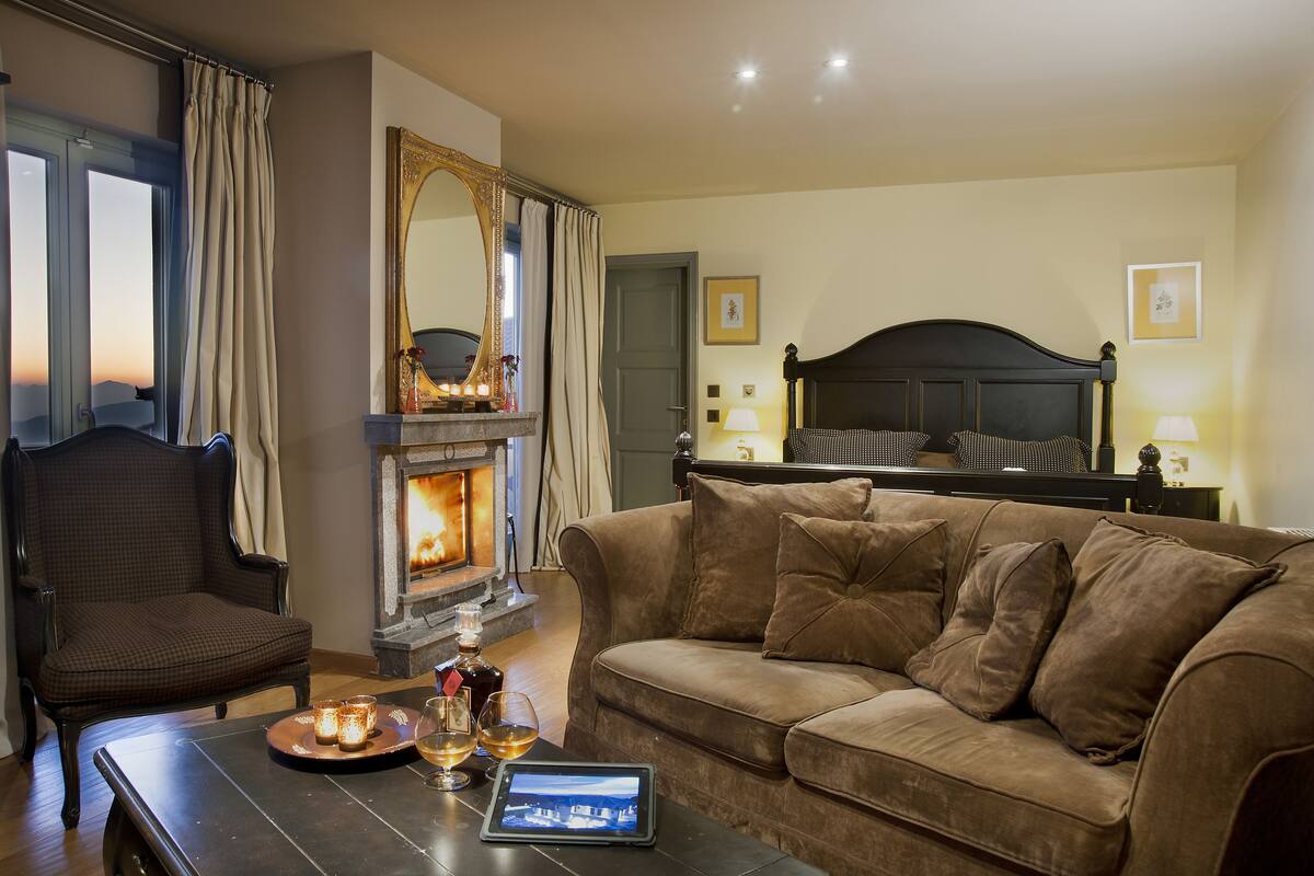 Ein gemütliches Wohnzimmer mit Kamin, einer Couch, einem Sessel und einem Tablet auf einem Couchtisch.