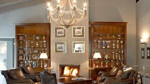 A spacious living room with a checkered floor, leather sofas, a chandelier, and a fireplace.
