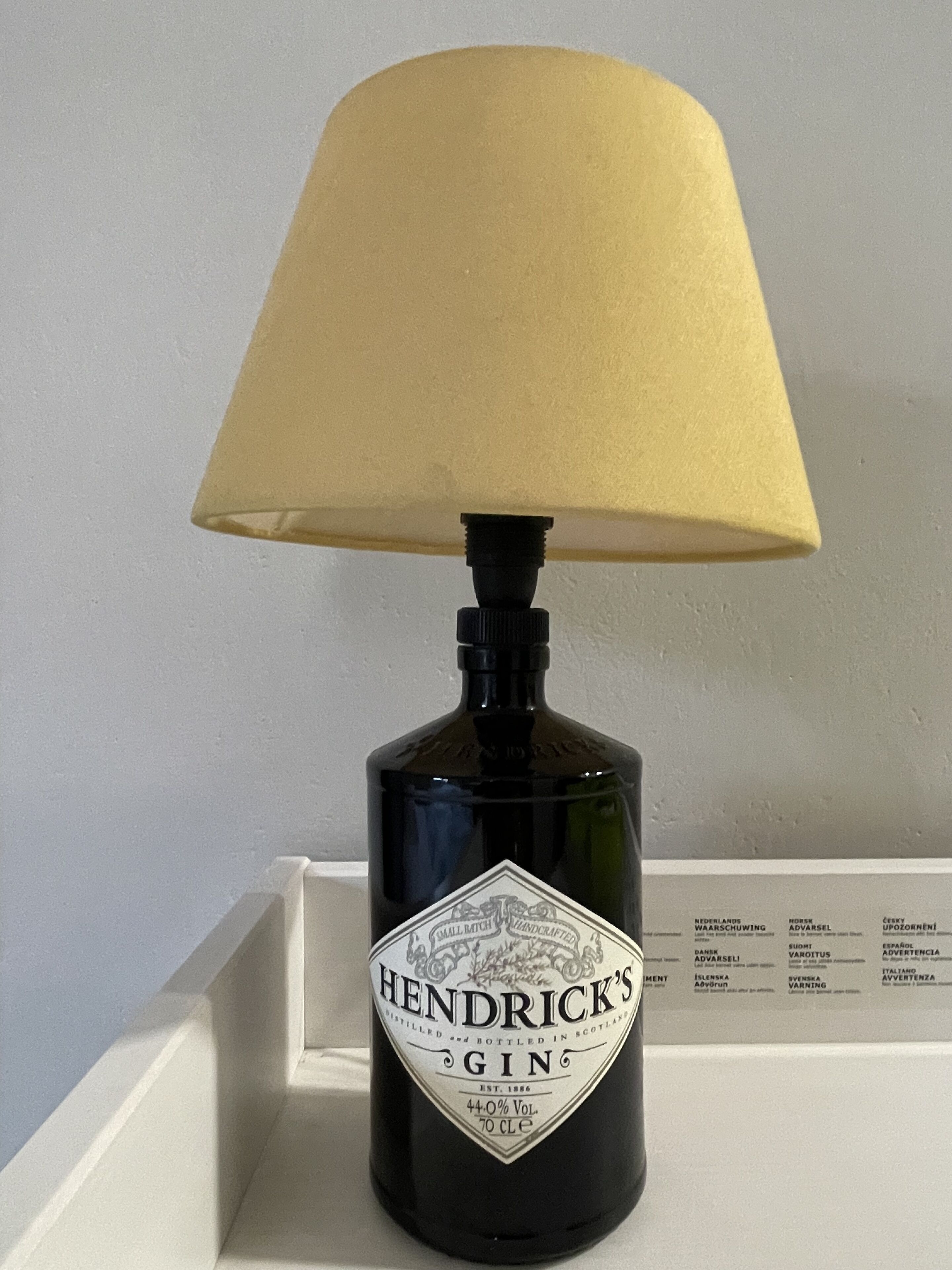 Una bottiglia di Hendrick's Gin sormontata da un paralume color beige.