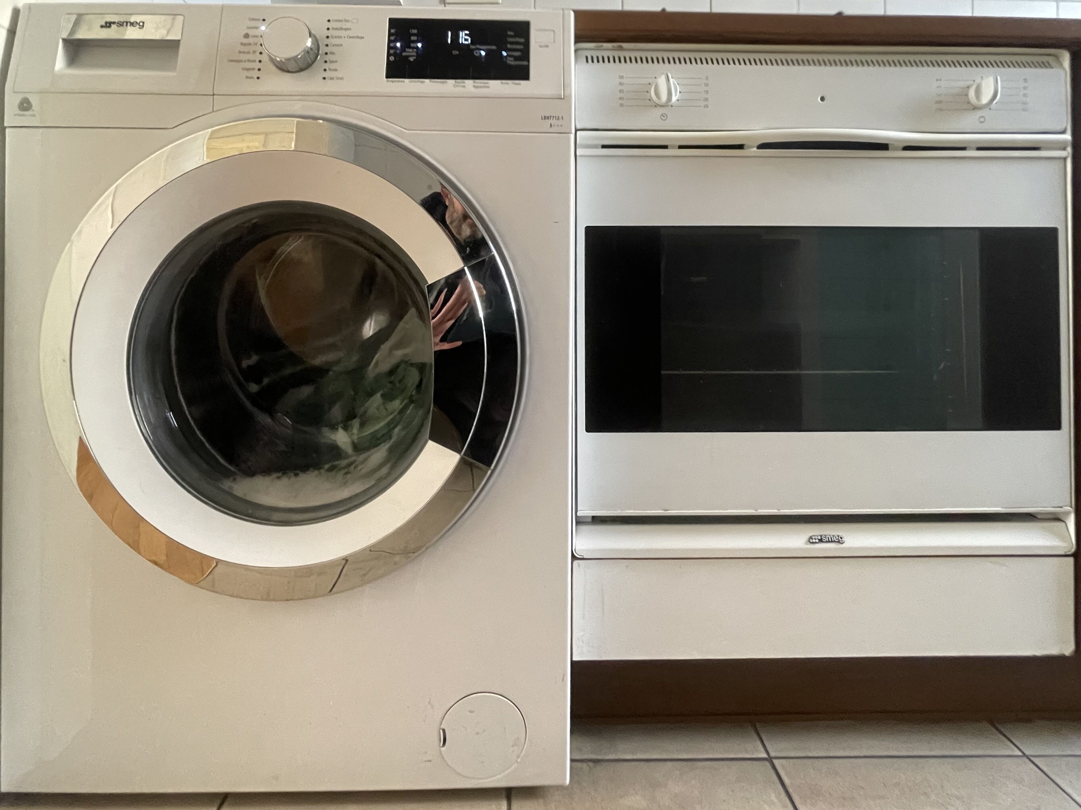 A front-loading washing machine and a built-in oven in a kitchen.