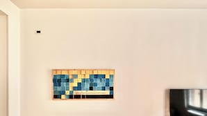 Una pared con un cuadro enmarcado que muestra una cuadrícula de cuadrados azules y amarillos y una cita.