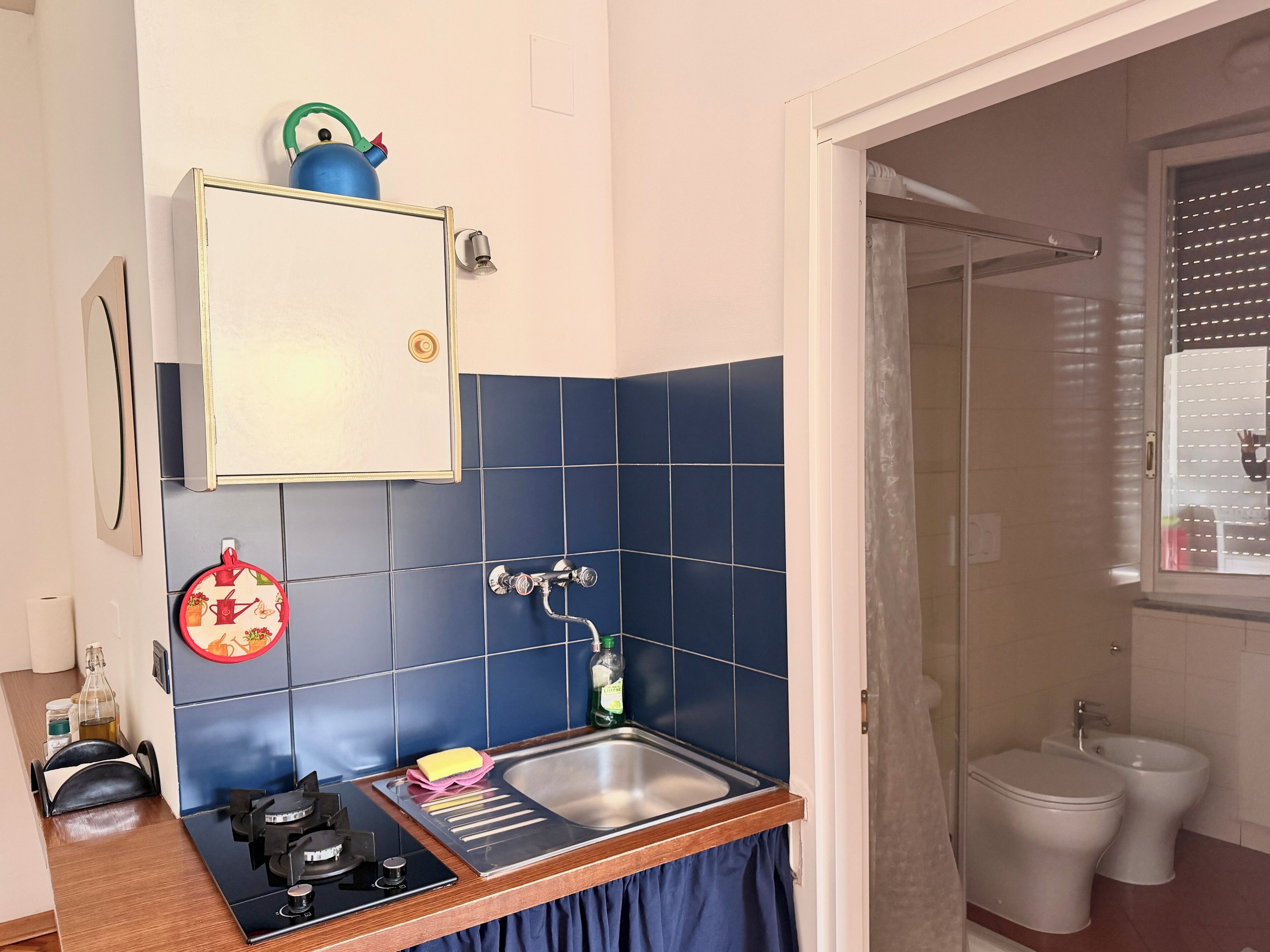 A compact kitchen with a gas stove, sink, and blue-tiled backsplash.