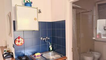 A compact kitchen with a gas stove, sink, and blue-tiled backsplash.