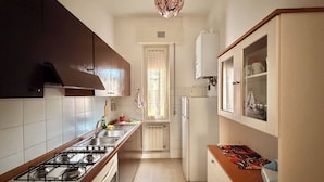 Una cocina con estufa a gas, lavamanos, armarios y refrigerador.
