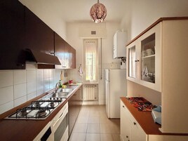 Una cocina con estufa a gas, lavamanos, armarios y refrigerador.