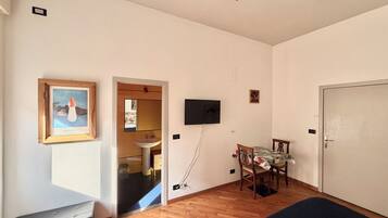 Een kamer met een bed, bureau, stoel, televisie en een deur.