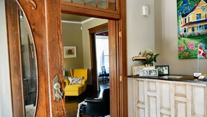 A room with a wooden door, a yellow armchair, a black chair, a white cabinet, and a painting on the wall. - Three Danes Inn (Fort Worth)