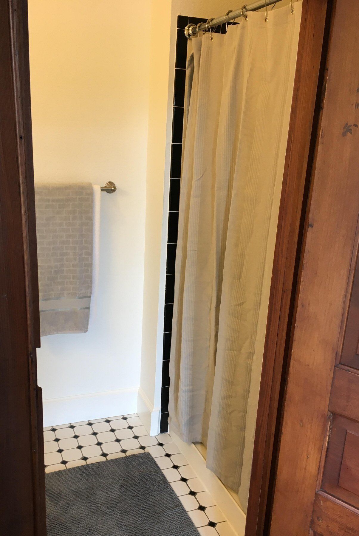 A bathroom with a shower curtain, a towel rack, and a patterned floor.