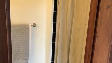 A bathroom with a shower curtain, a towel rack, and a patterned floor.