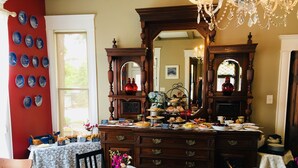 A dining area with a wooden buffet table, floral centerpiece, and a red accent wall. - Three Danes Inn (Fort Worth)