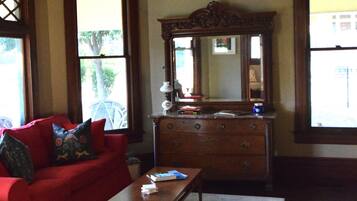A living room with a red sofa, wooden coffee table, and a dresser with a mirror.