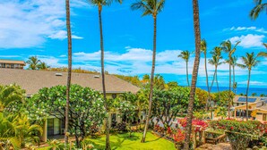 A tropical resort with palm trees, a well-maintained lawn, and a view of the ocean. - Kihei Akahi (Kihei)