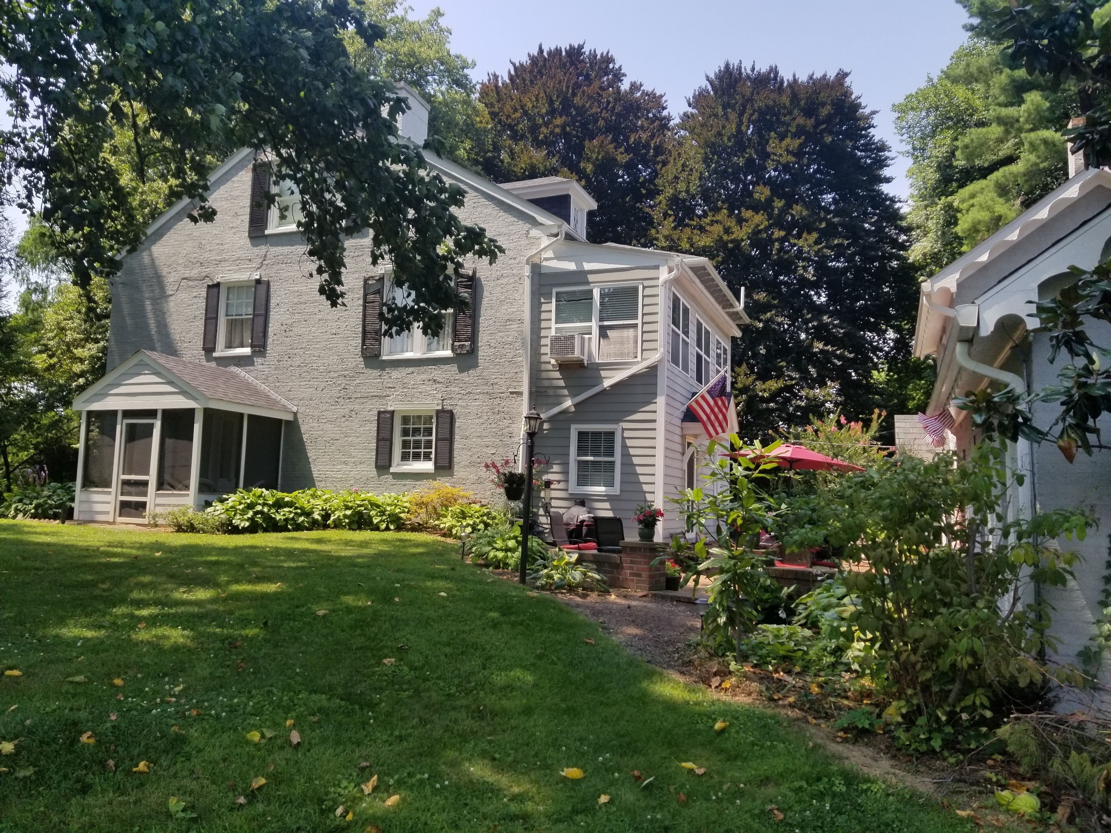 A two-story house with a porch, a small garden, and an American flag.