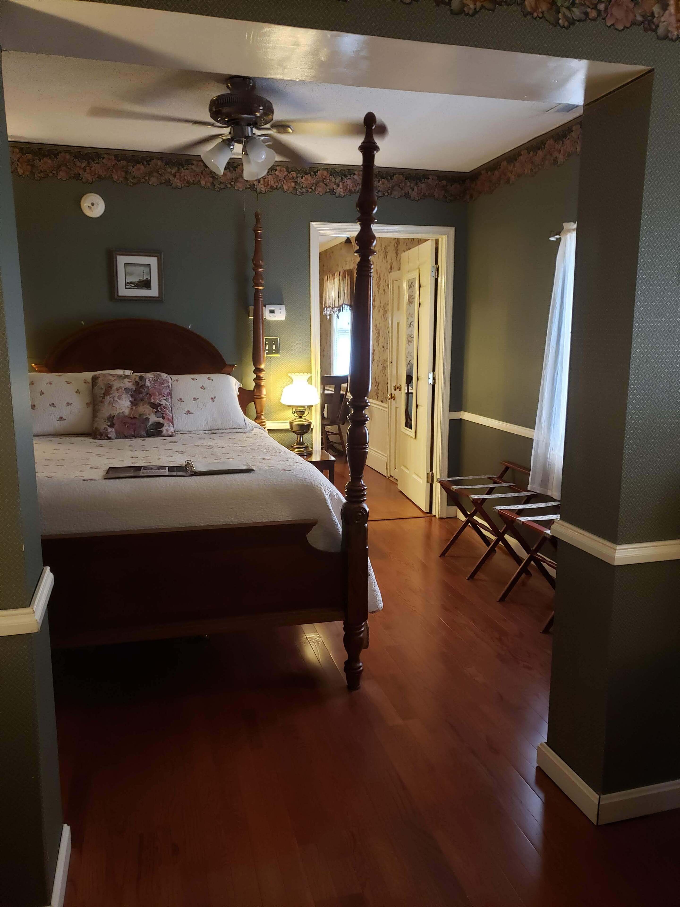 A bedroom with a four-poster bed, a ceiling fan, and a nightstand with a lamp.