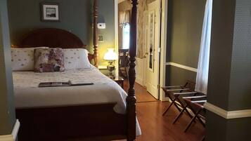 A bedroom with a four-poster bed, a ceiling fan, and a nightstand with a lamp.