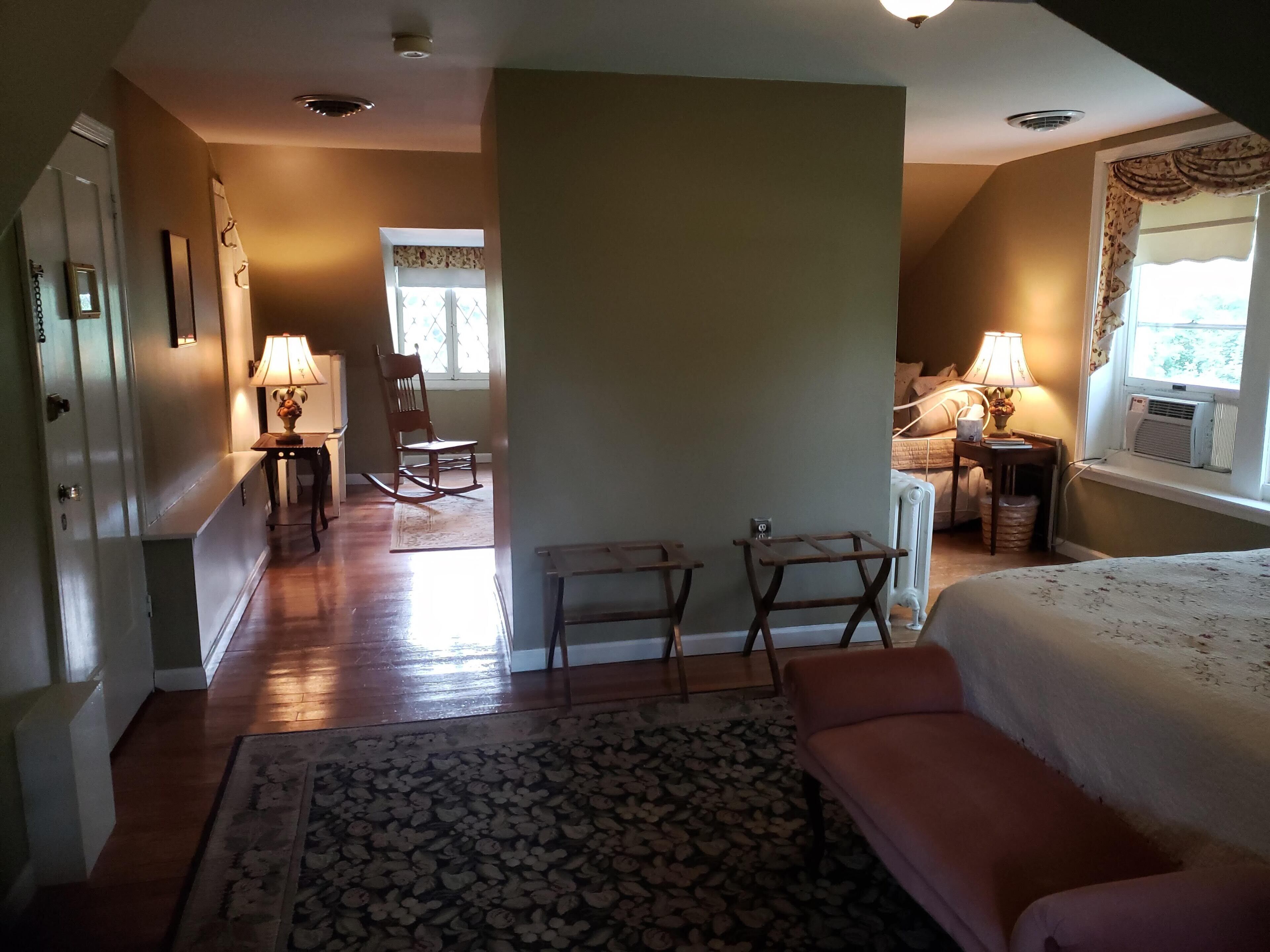 A room with a bed, a rocking chair, a small table, and a radiator.
