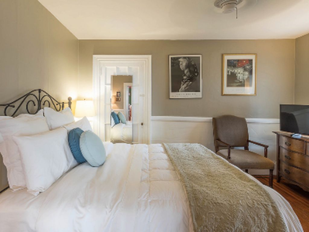 Een slaapkamer met een bed, een stoel, een dressoir en een televisie.