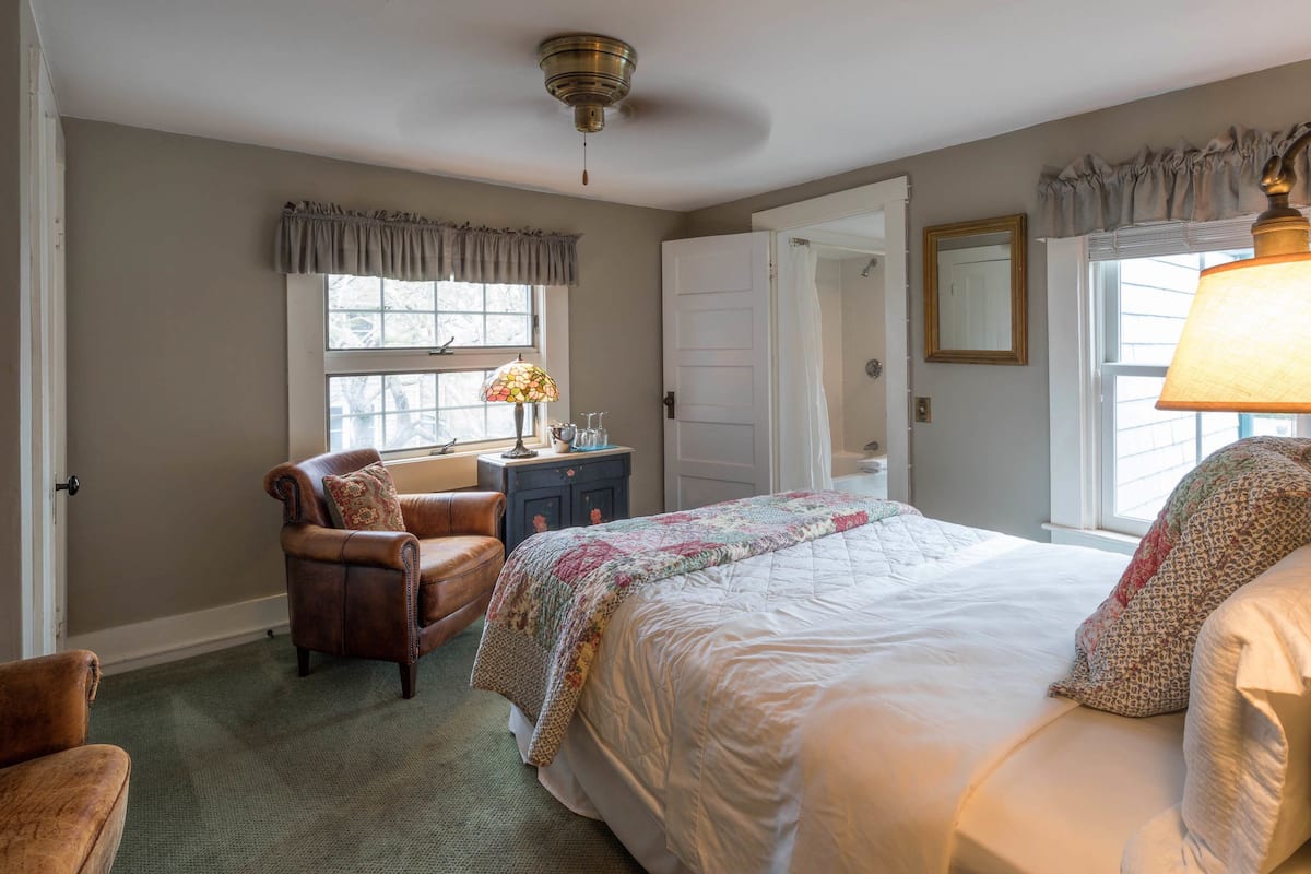 Ein Schlafzimmer mit Bett, Stuhl, Schreibtisch und Fenster.