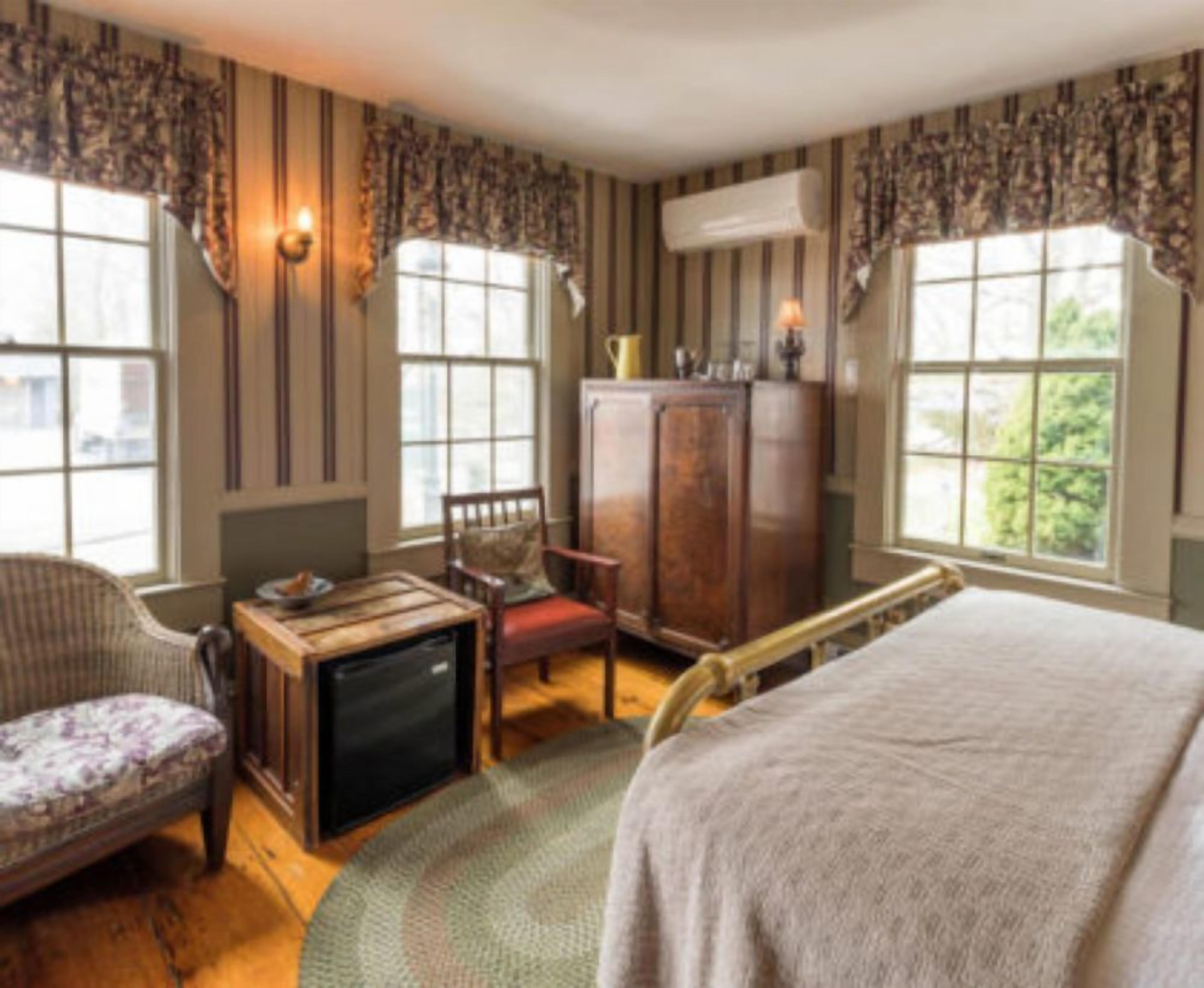 A room with a bed, a wooden cabinet, a chair, a small table, and a television.