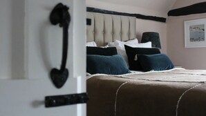 A bedroom with a bed, a headboard, a wall-mounted picture, and a door with a heart-shaped handle. - Nags Head (Great Missenden)