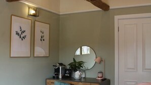 A bedroom with a bed, a desk, a chair, a mirror, and a door.