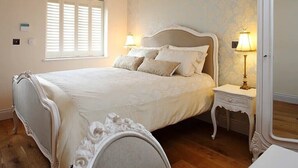 A bedroom with a bed, two bedside tables, a window with shutters, and a mirror. - Nags Head (Great Missenden)