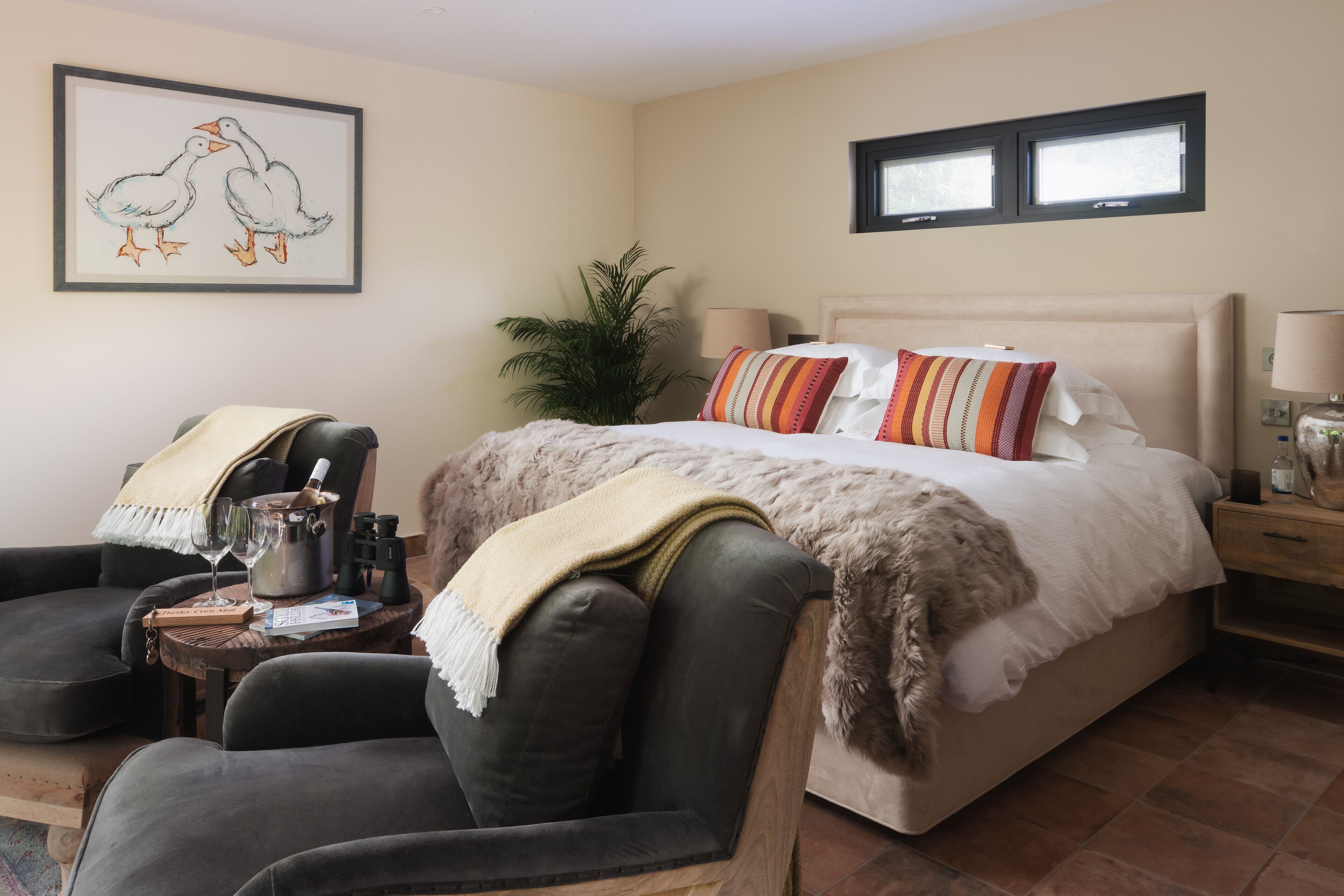 A bedroom with a bed, a chair, a lamp, and a framed picture on the wall.