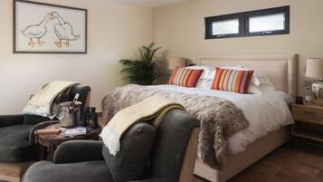 A bedroom with a bed, a chair, a lamp, and a framed picture on the wall.