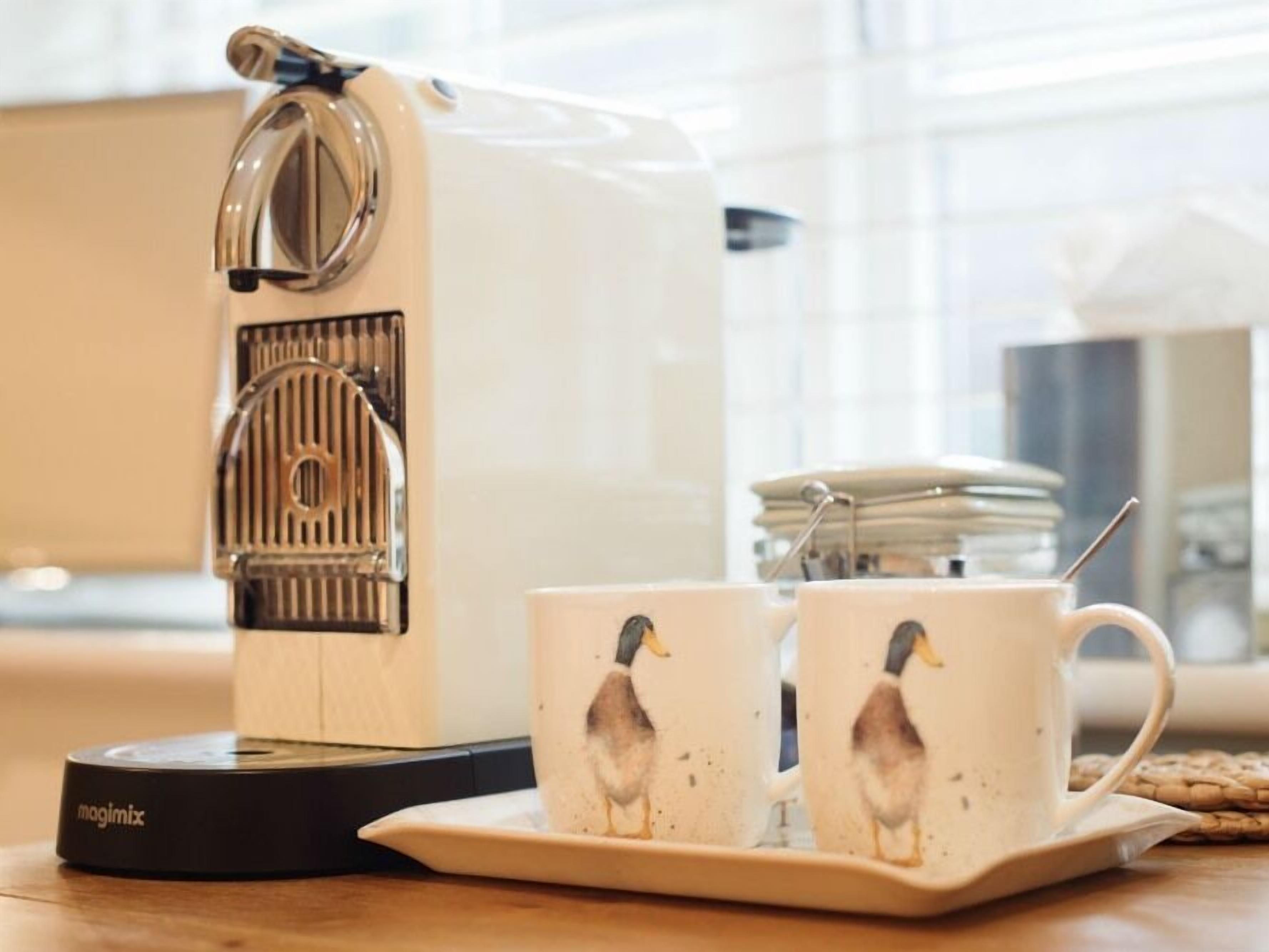 A coffee maker with two cups on a tray.
