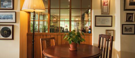 A dining area with a round wooden table, two chairs, a potted plant, and a floor lamp.