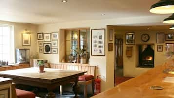 A cozy dining area with a wooden table and chairs, a fireplace, and framed pictures on the walls.
