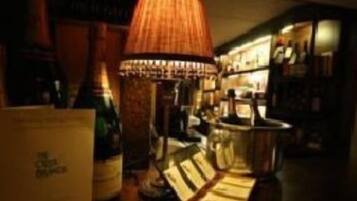 A dimly lit bar area with a large, textured lamp, a bar counter, and shelves stocked with bottles.