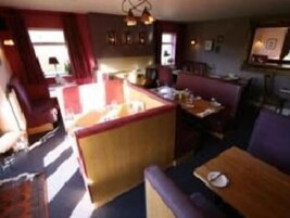 Un restaurante acogedor con cabinas y una zona de bar.