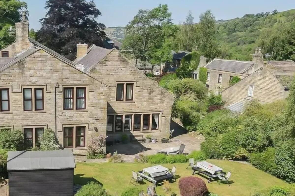 A stone building with multiple windows and a garden area with outdoor seating.