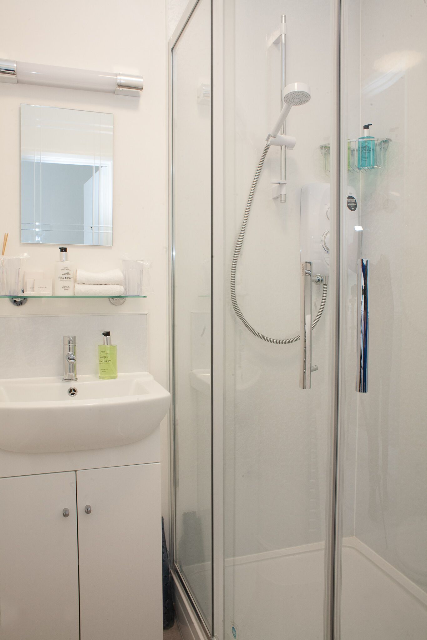 A modern bathroom with a glass-enclosed shower, a white sink, and a mirror above the sink.