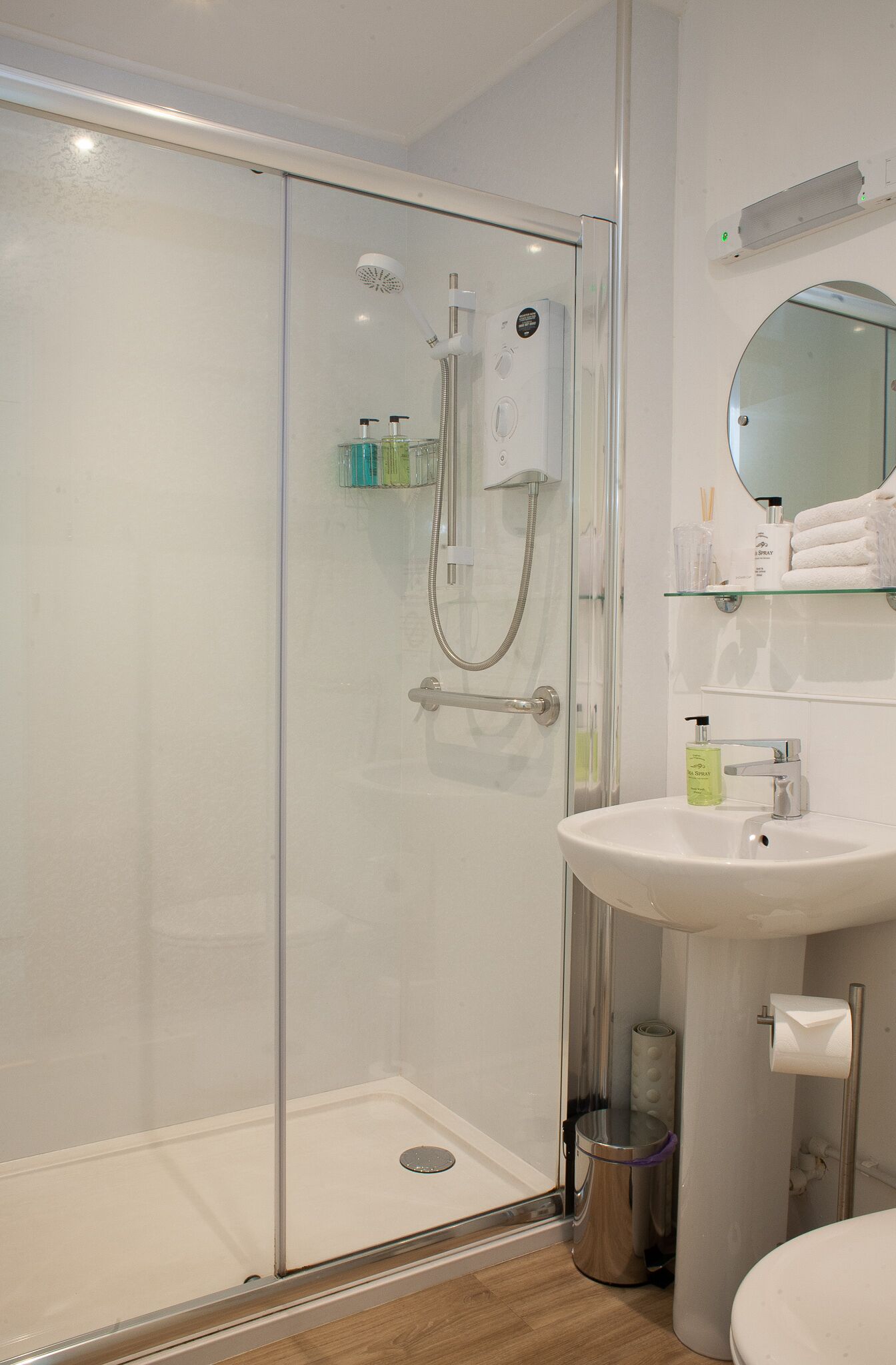 A modern bathroom with a glass shower enclosure, a white sink, and a mirror above the sink.