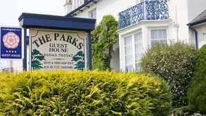 En skylt för ”The Parks Guest House” med kontaktuppgifter och en lista över tillgängliga tjänster.