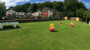 A grassy outdoor area with a pool table, a stone building, and a restaurant named Rusland Pool.