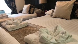 A hotel room with two beds, each with neatly folded towels and a brown decorative runner.
