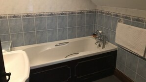 A bathroom with a bathtub, a sink, and a towel rack. - The Swan Hotel Smoke & Taphouse (Telford)