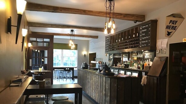 A bar area with stools, a counter, and a menu board. - The Swan Hotel Smoke & Taphouse (Telford)