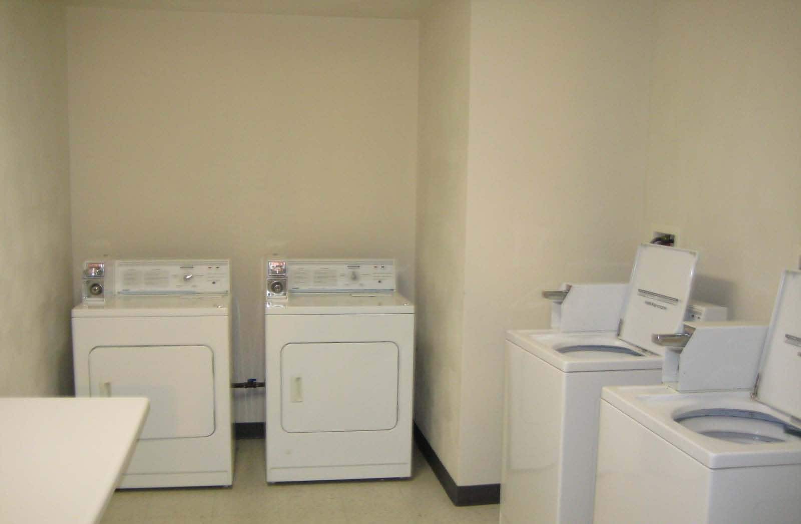 A laundry room with two front-loading washers and two dryers.
