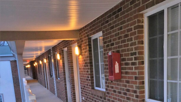 A long corridor with a brick exterior, white railings, and evenly spaced windows. - Affordable Suites Burlington (Burlington)