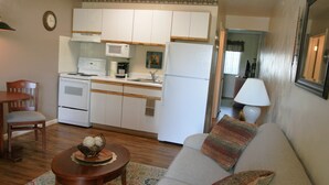 A compact living space with a kitchenette, a sofa, a dining table, and a chair. - Affordable Suites Burlington (Burlington)
