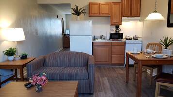 A compact living space with a kitchenette, a sofa, a dining table, and a lamp.