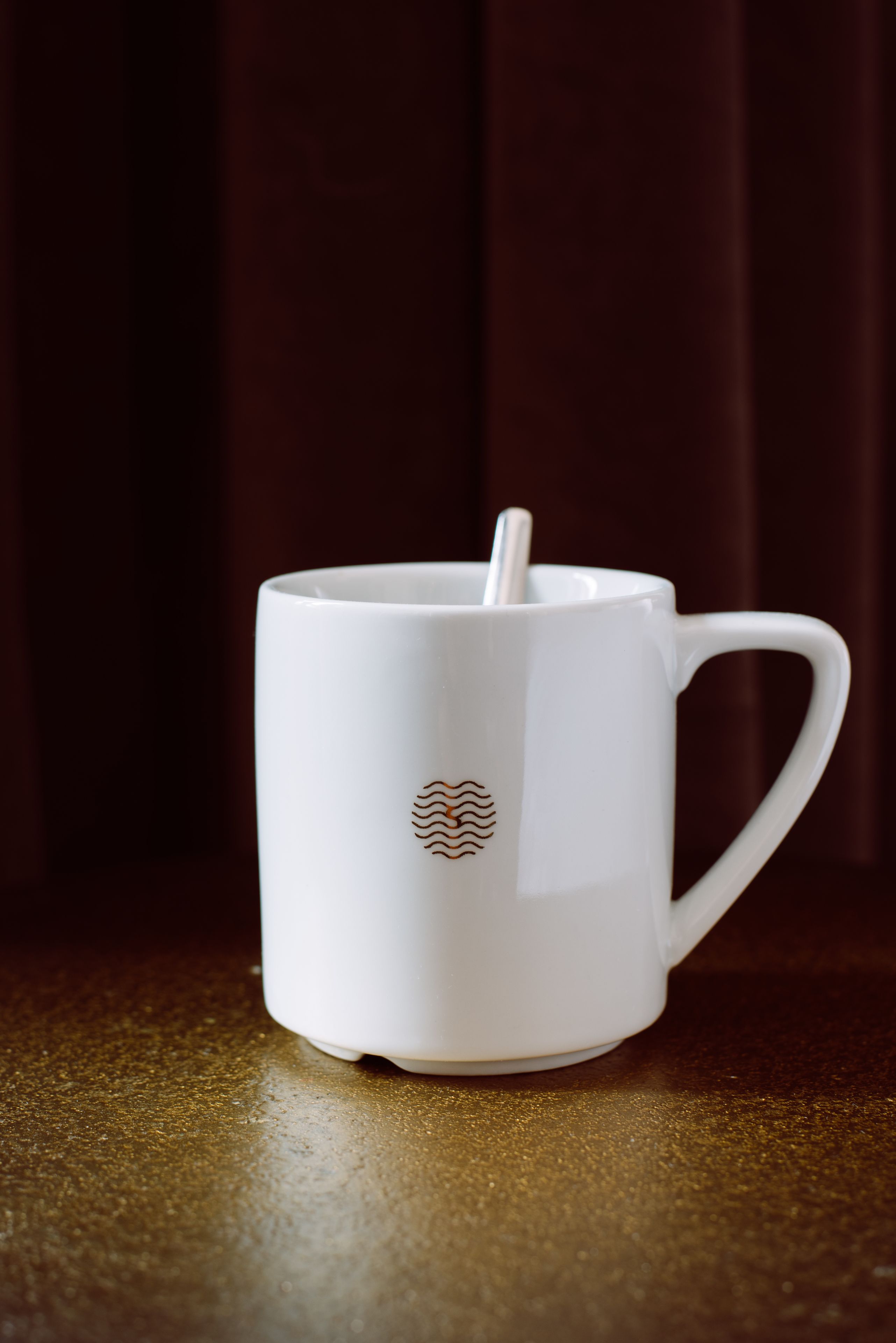 Eine weiße Keramiktasse mit Henkel auf einer strukturierten Oberfläche.