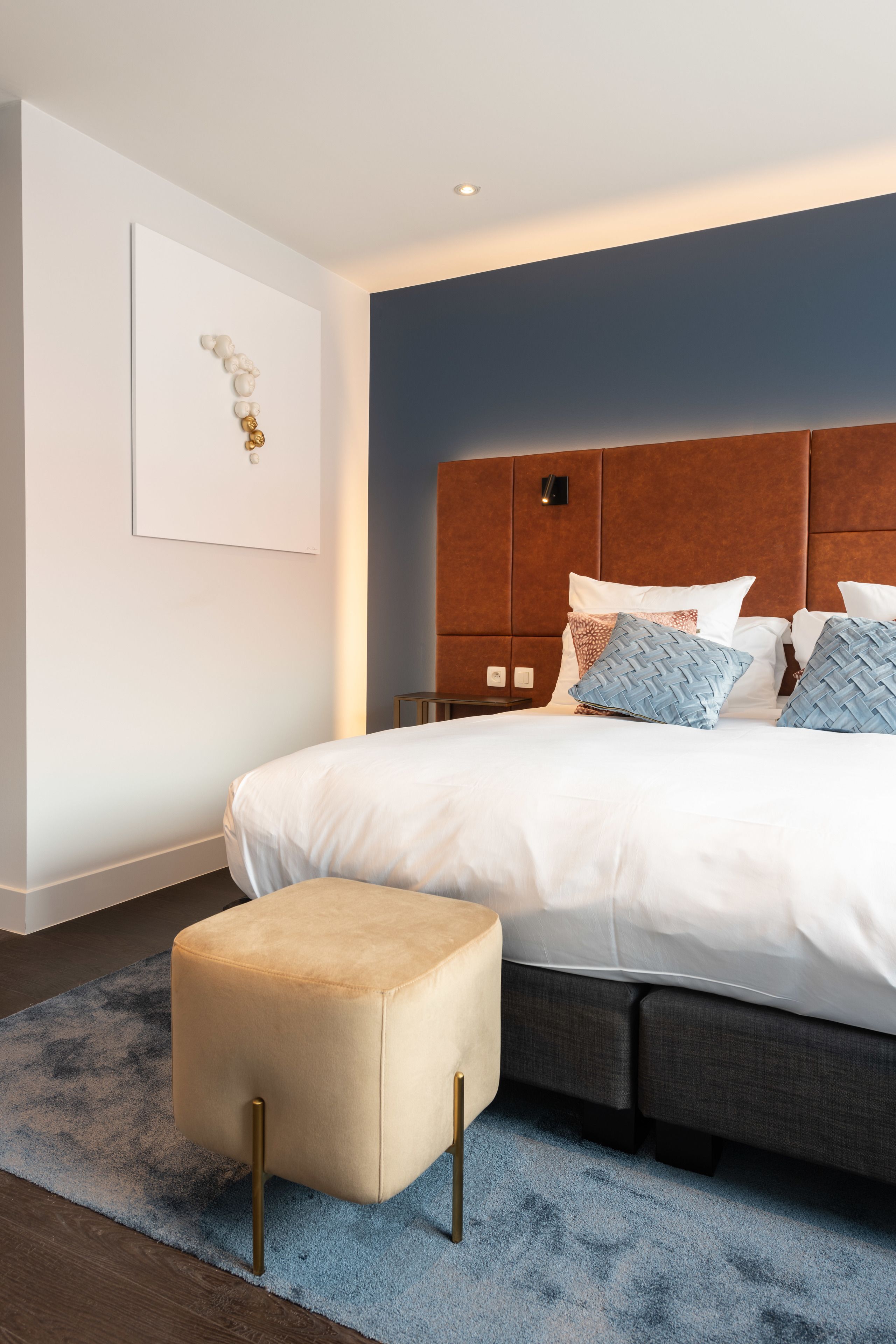 Ein modernes Schlafzimmer mit einem großen Bett, einem Kopfteil mit integrierter Beleuchtung, einem Nachttisch und einer Wanddekoration.