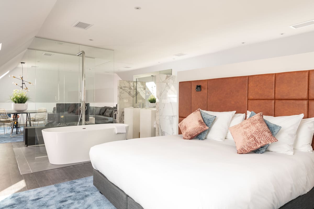 Ein modernes Schlafzimmer mit einem großen Bett, einer Duschkabine und einer Sitzecke mit einer Couch und einem kleinen Tisch.
