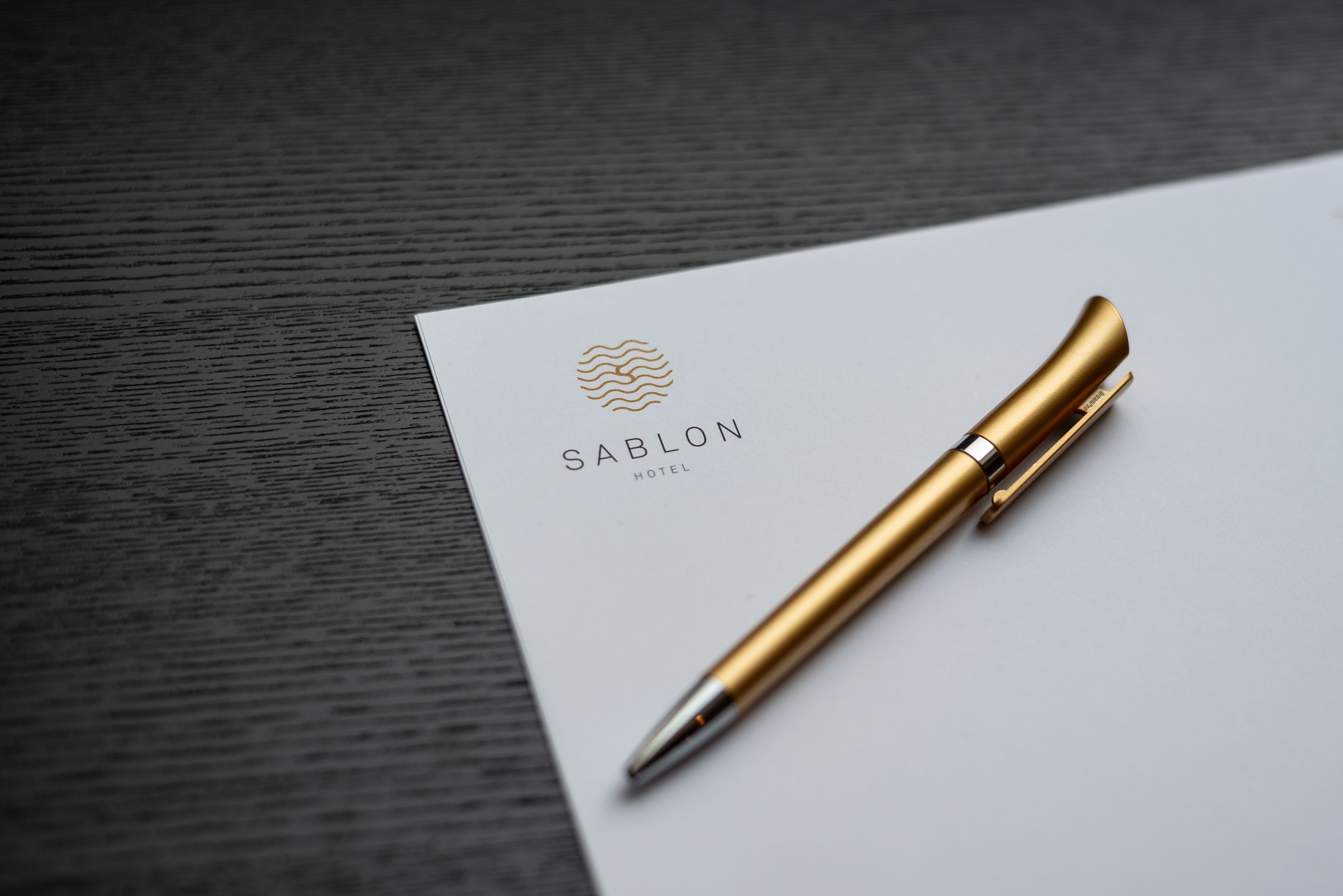 Un stylo sur une carte de visite avec le texte « HÔTEL SABLON ».